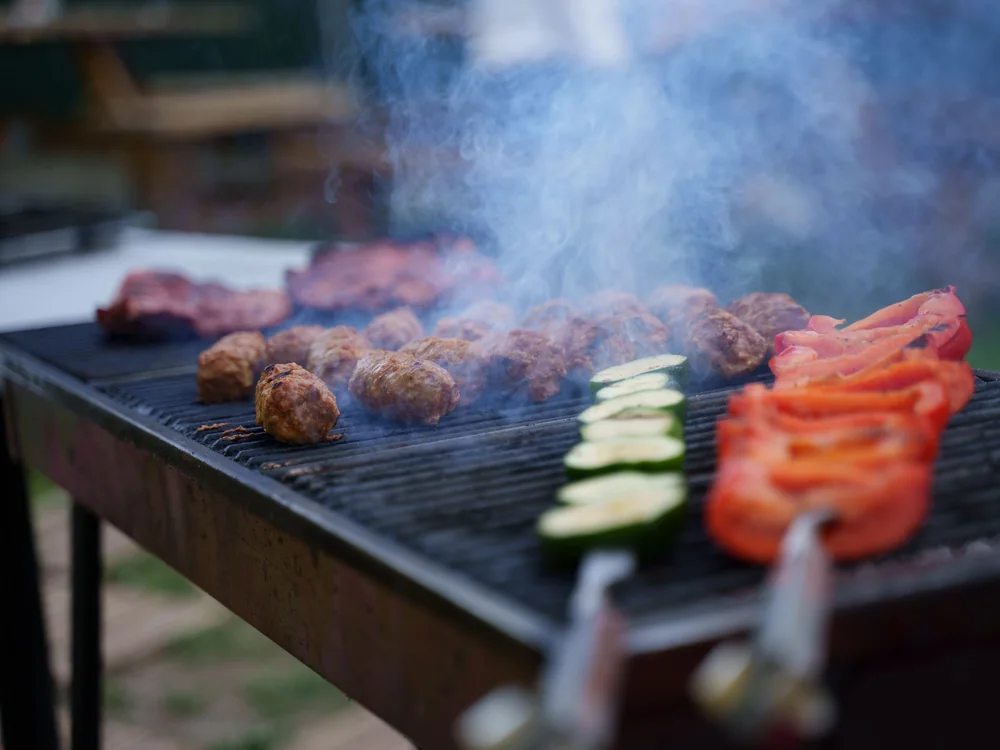 Grilled meat and vegetables cooking over an open charcoal grill